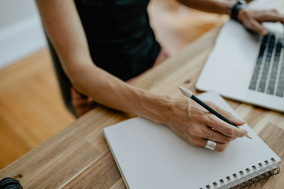 woman writing in notebook at desk